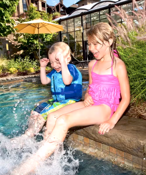 Two children kicking their feet in Biosphere pool.